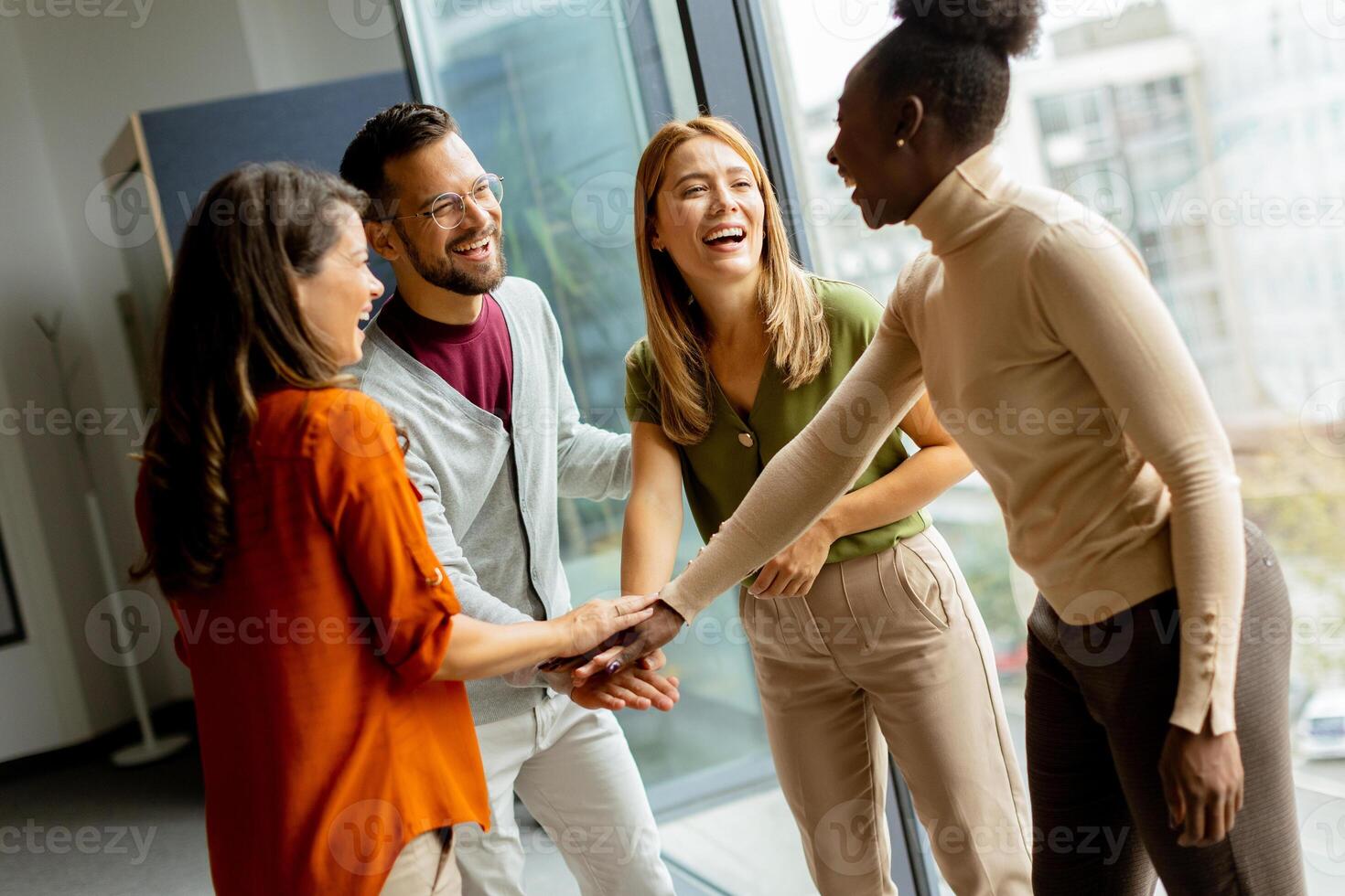 joven multiétnico puesta en marcha equipo sostener manos juntos en el moderno oficina foto