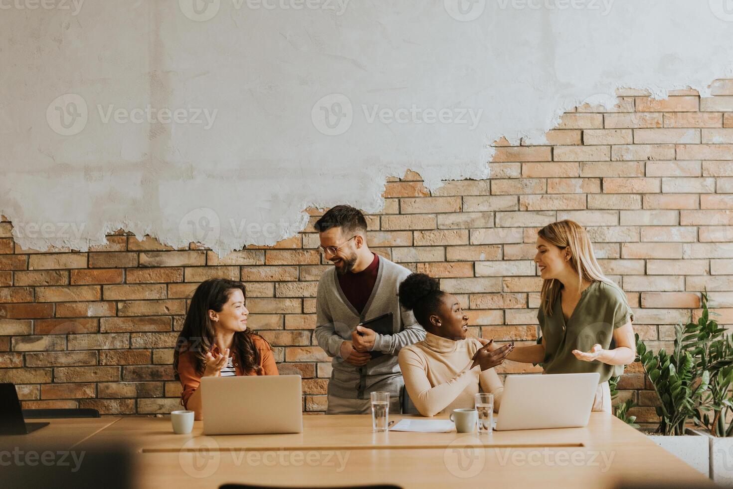 Young multiethnic startup team working by the brick wall in the industrial style office photo