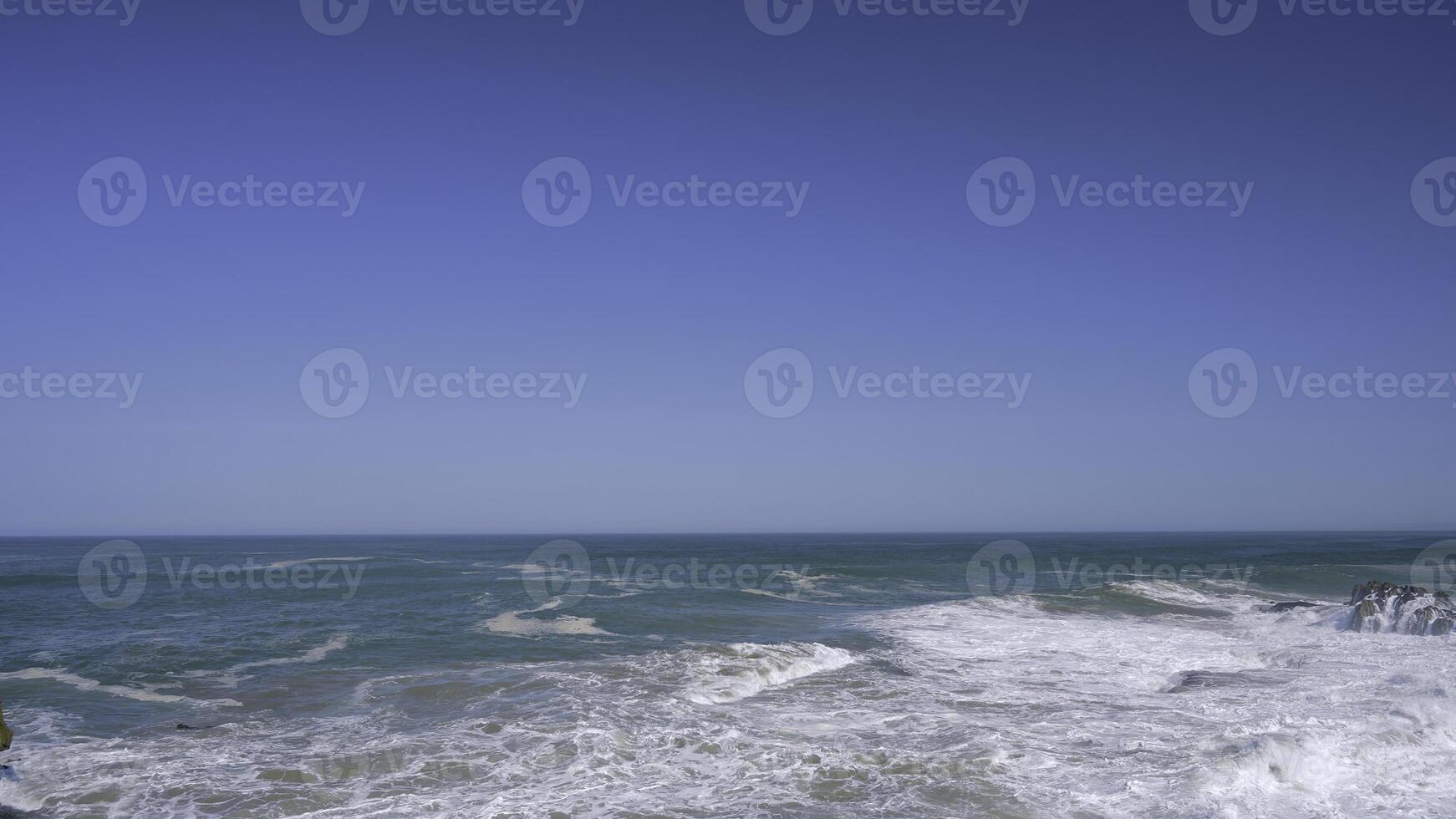 Storming sea . Action . Blue transparent water that is thrown out by waves to the shore against the background of a blue cloudless sky. photo