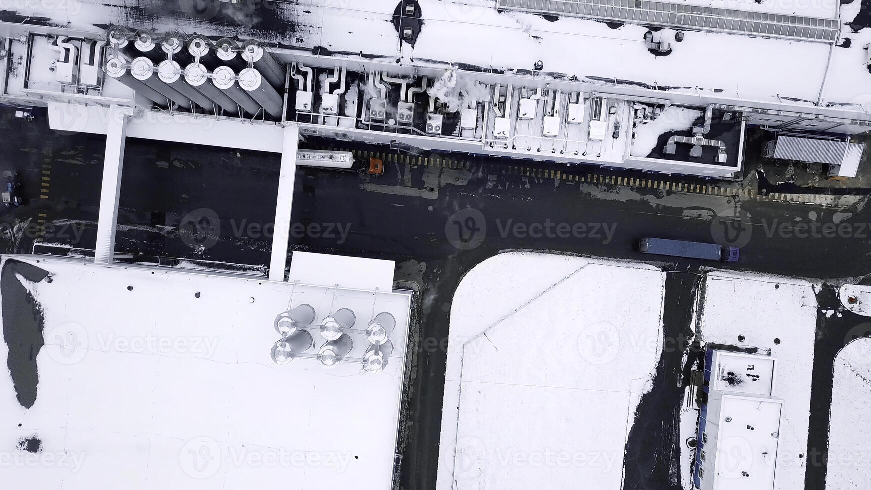 View from a helicopter. Creative. Long bright-colored trucks that move next to industrial plants turning in different directions. photo