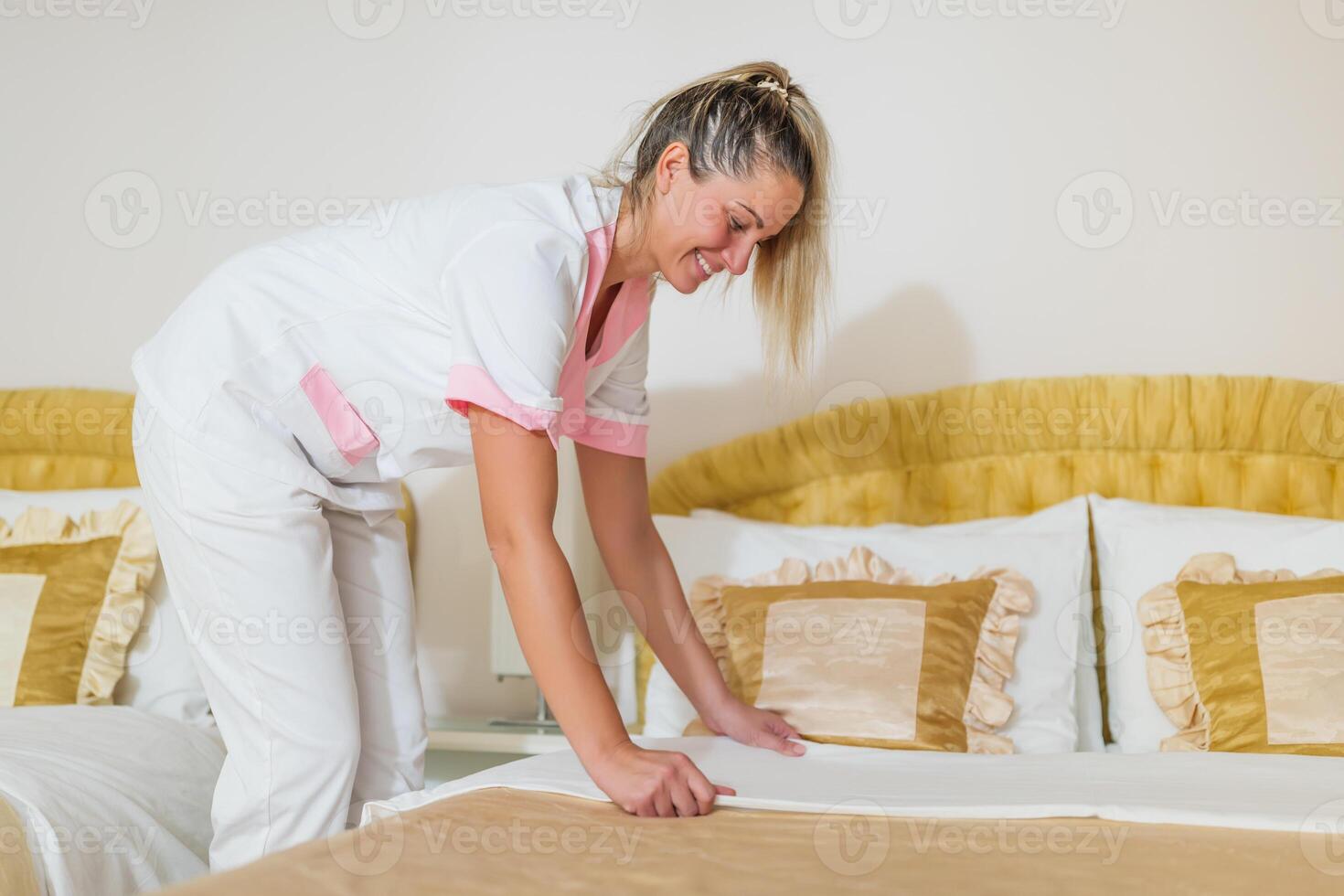 Beautiful hotel maid making bed in a room. photo