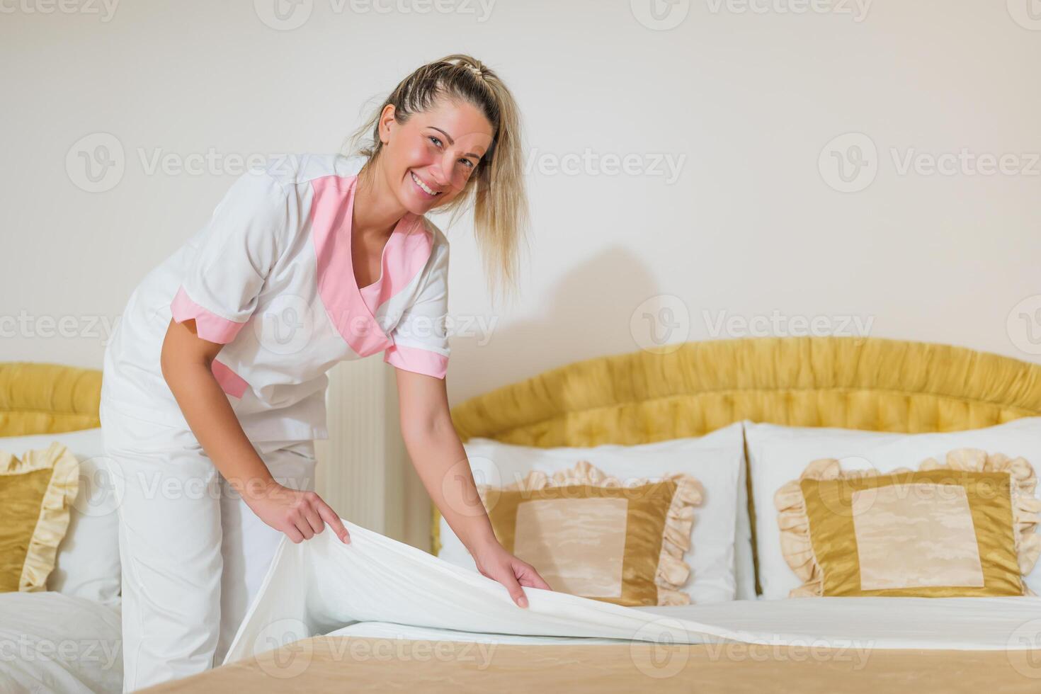 Beautiful hotel maid making bed in a room. photo