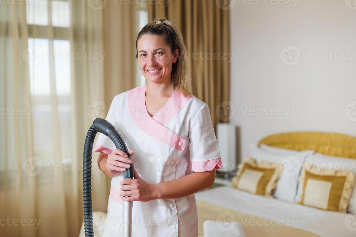 Beautiful hotel maid vacuuming room. photo