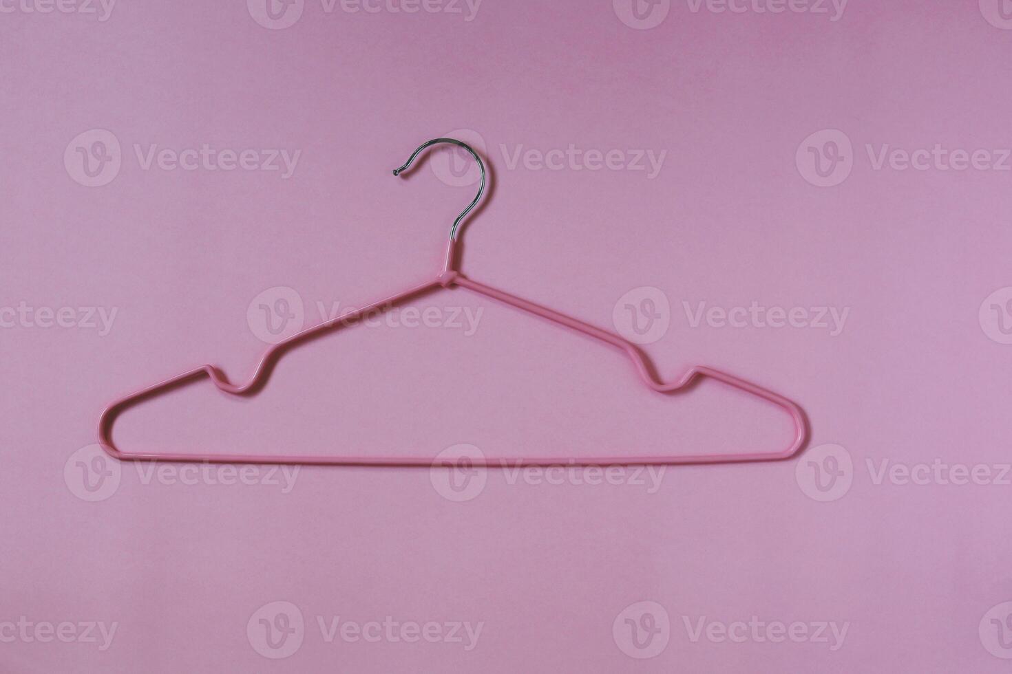 Clothes hangers on pink background photo