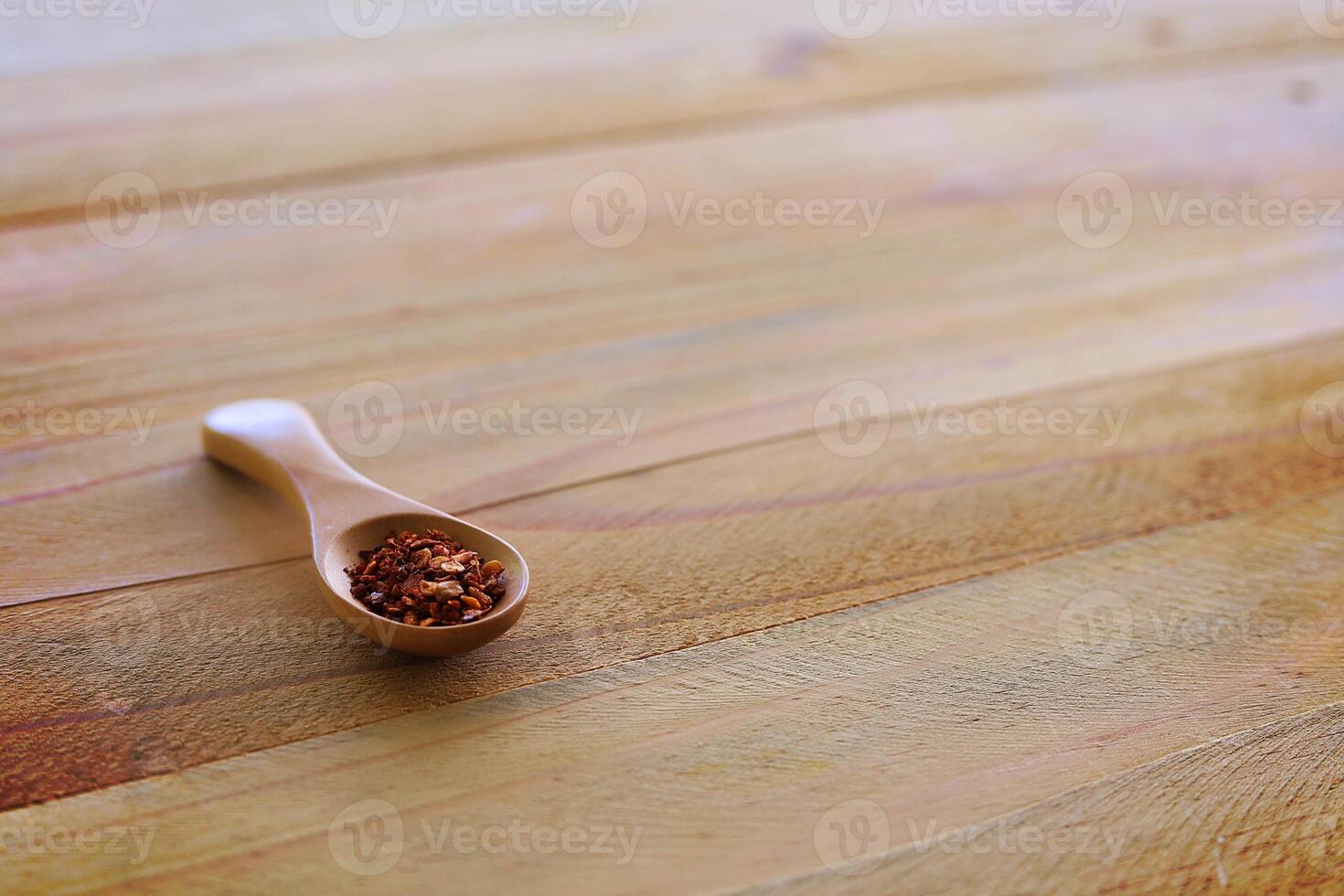 A spoon of cayenne pepper on wooden background photo