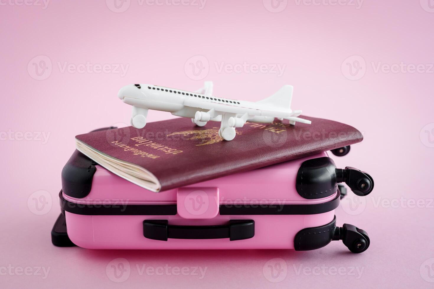 meñique equipaje con tailandés pasaporte y blanco avión modelo en rosado antecedentes foto