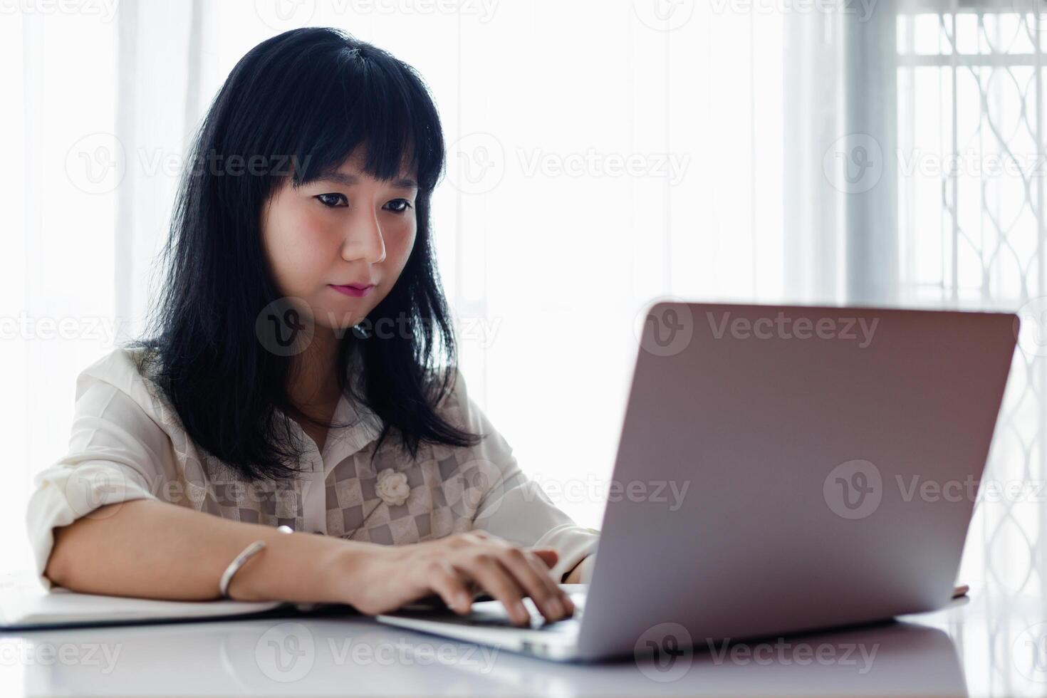 Asian woman using laptop and working at home photo