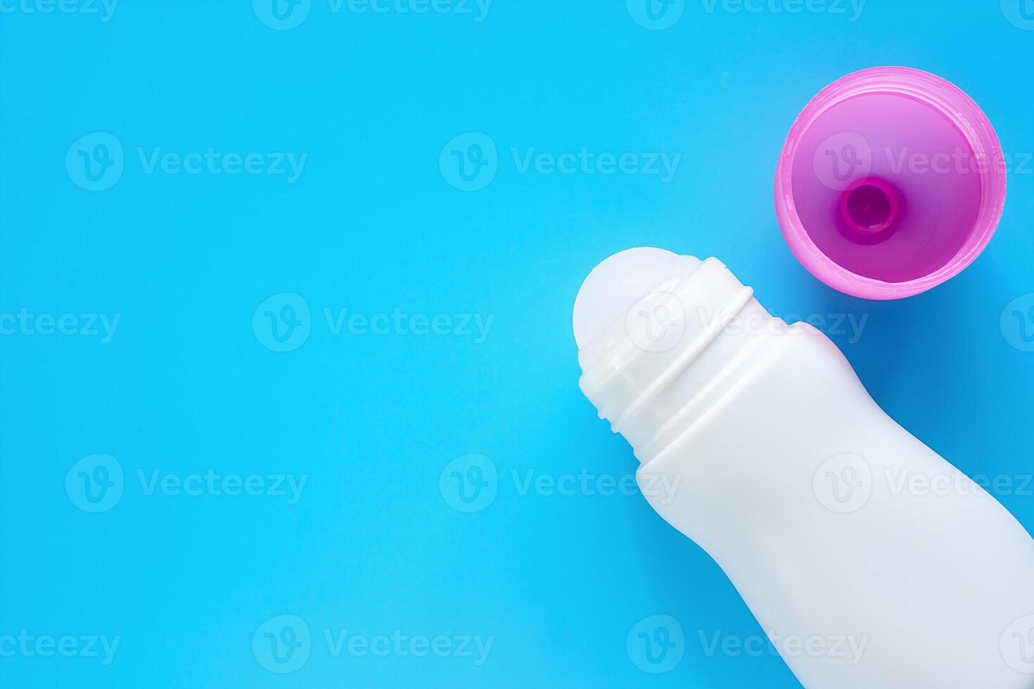 Female deodorant or roll on bottle with pink cover on blue background photo
