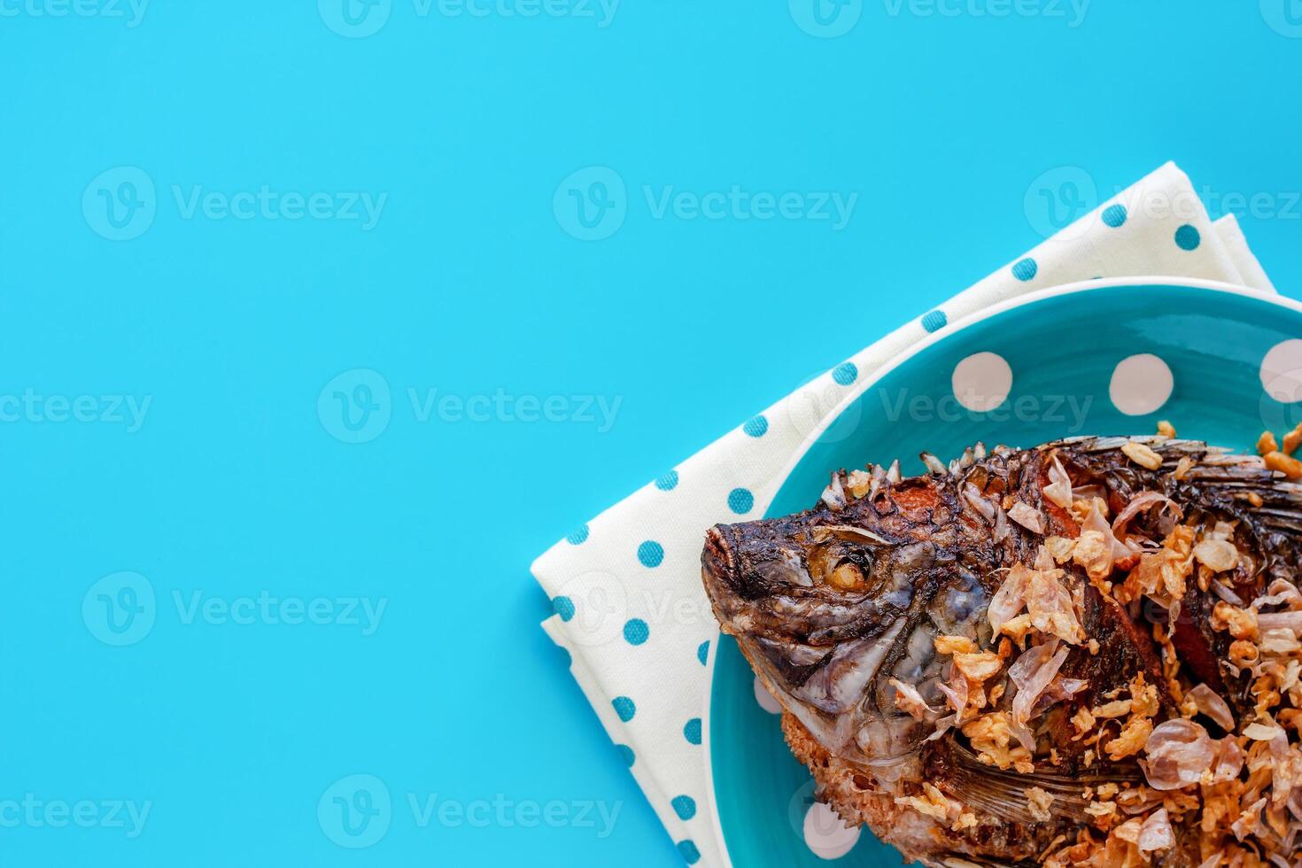 Delicious fried Tilapia fish in polka dot plate on blue background photo