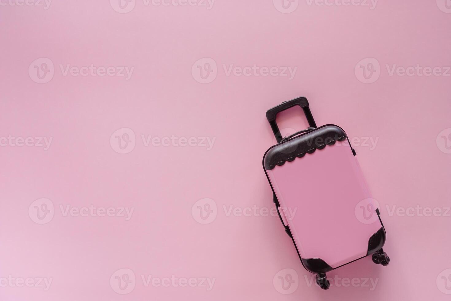 Mini pinky luggage toy model on pink pastel colored background photo