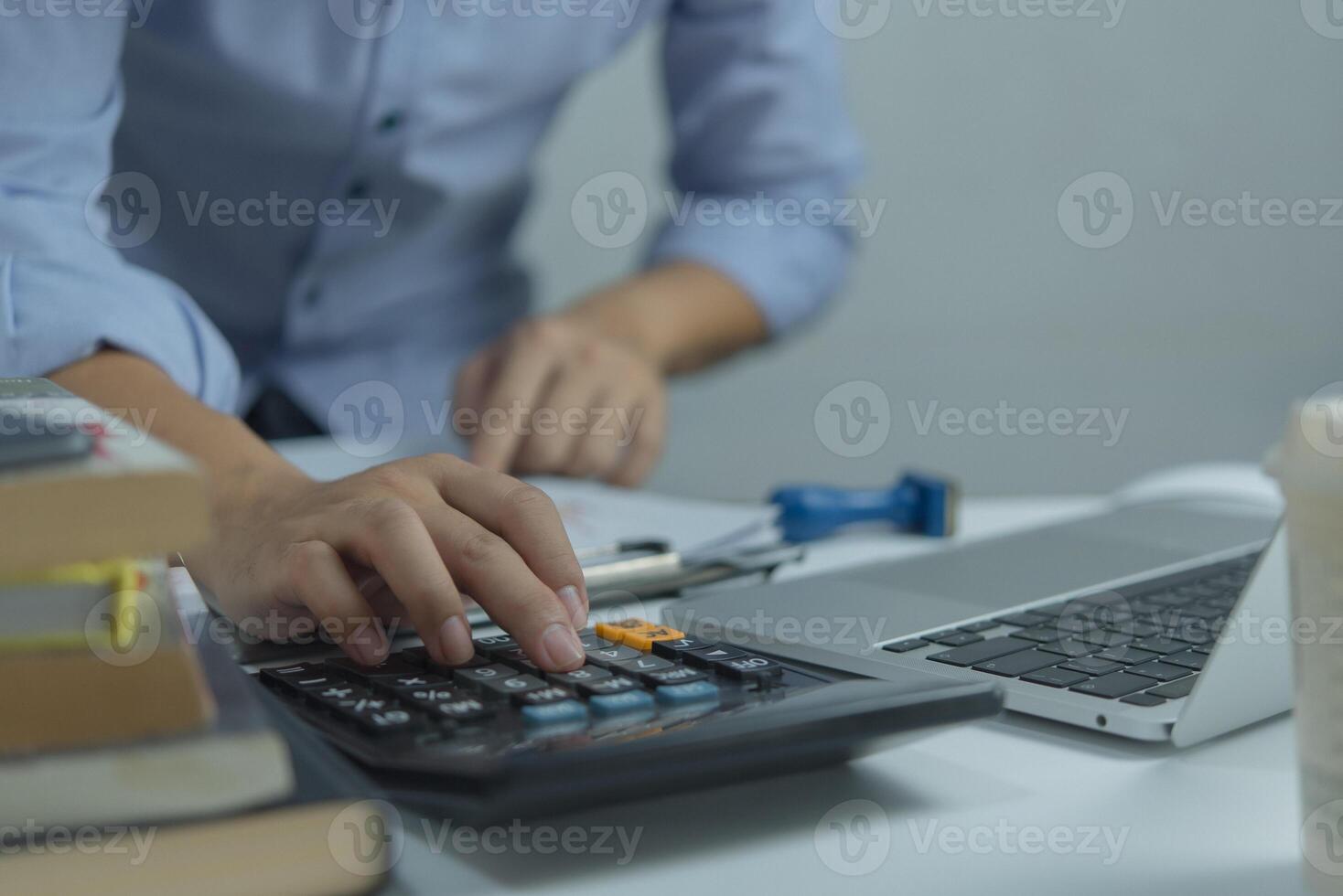 Businessman using calculator and accounting documents at desk with laptop computer. photo