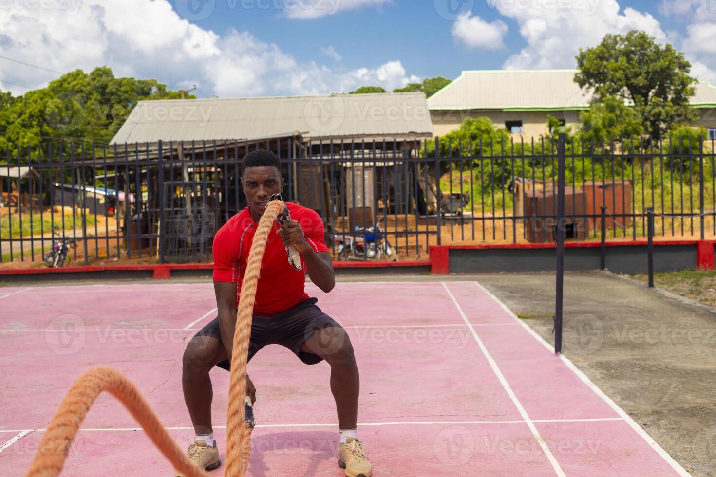 Young handsome man exercising using battle rope photo