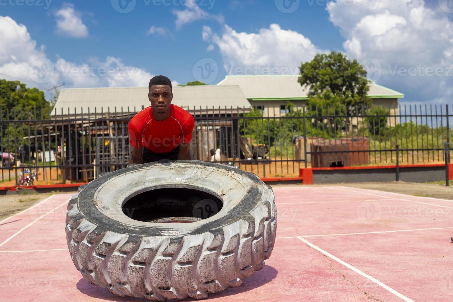 africano muscular hombre trabajando fuera en gimnasio voltear grande neumático foto