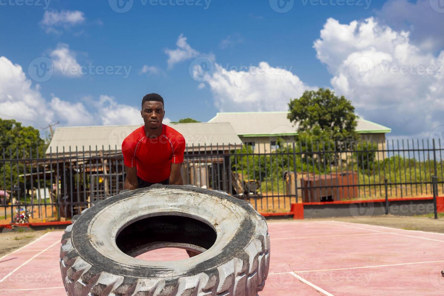 Muscular man working out in gym flipping big tire photo