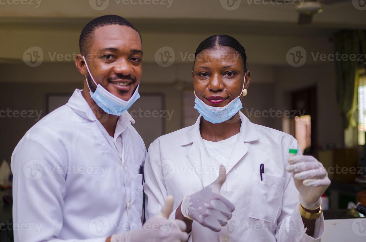 dos africano doctores sostener el vacuna en su mano y hizo pulgares arriba foto