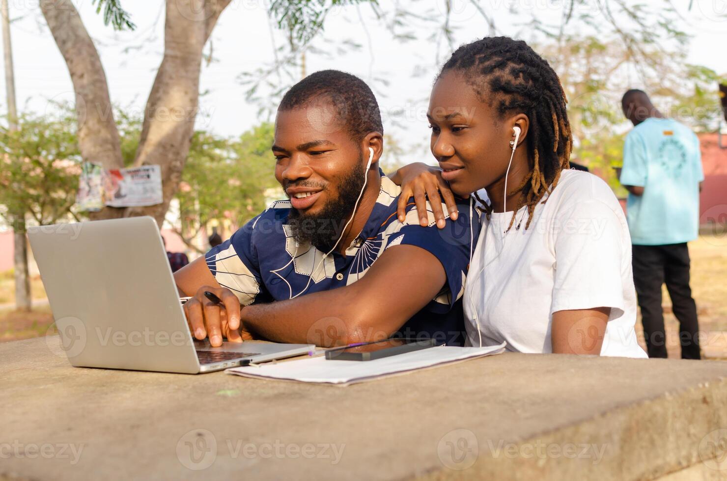 smiling couples outdoor using their laptop for shopping online photo