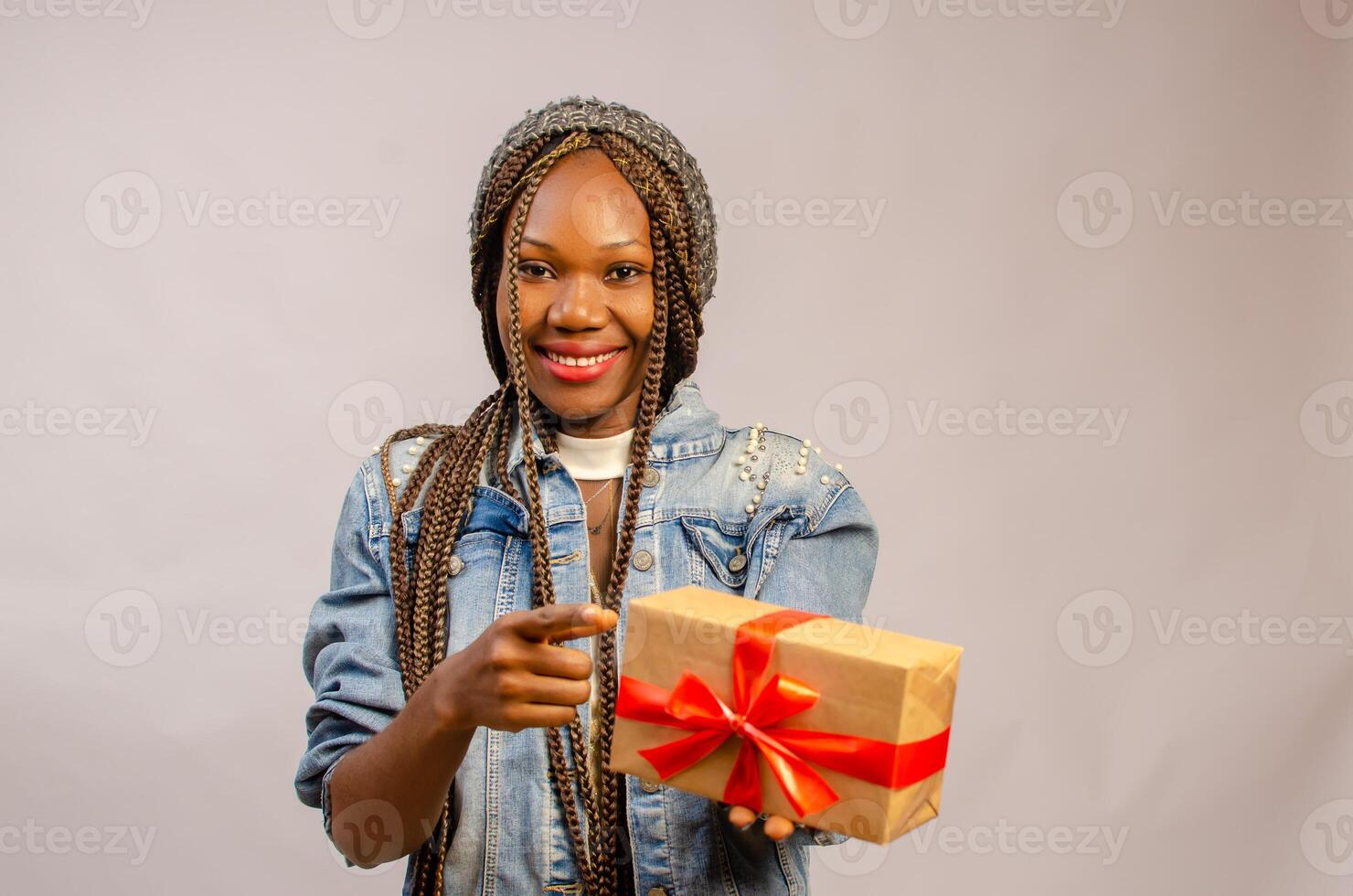 beautiful young lady smiling as she points to the present at her hand photo