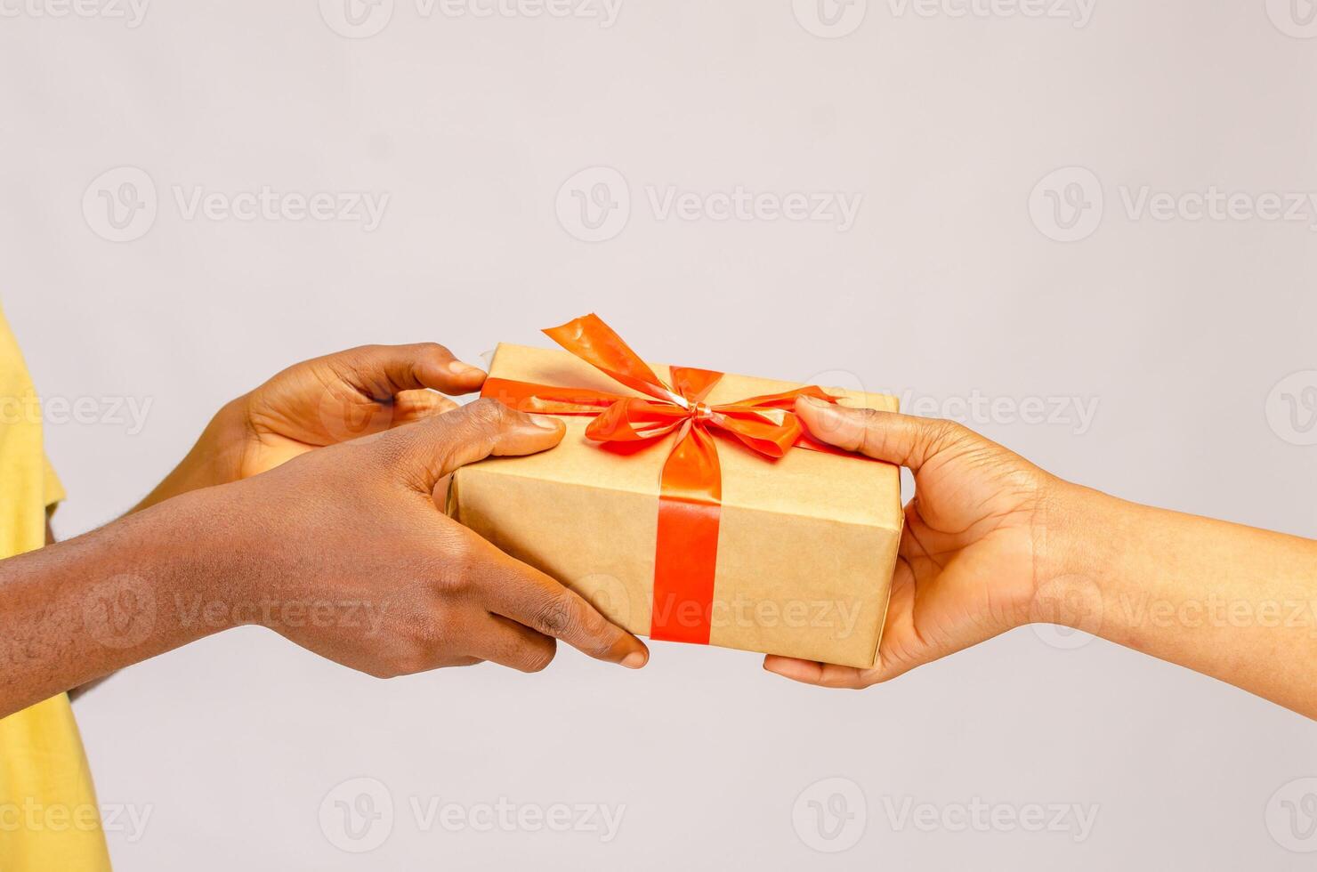 Holiday Celebration Concept. Closeup on female hands holding gift with red bow and giving present box to african american woman, greeting with Birthday, Christmas and New year at home photo