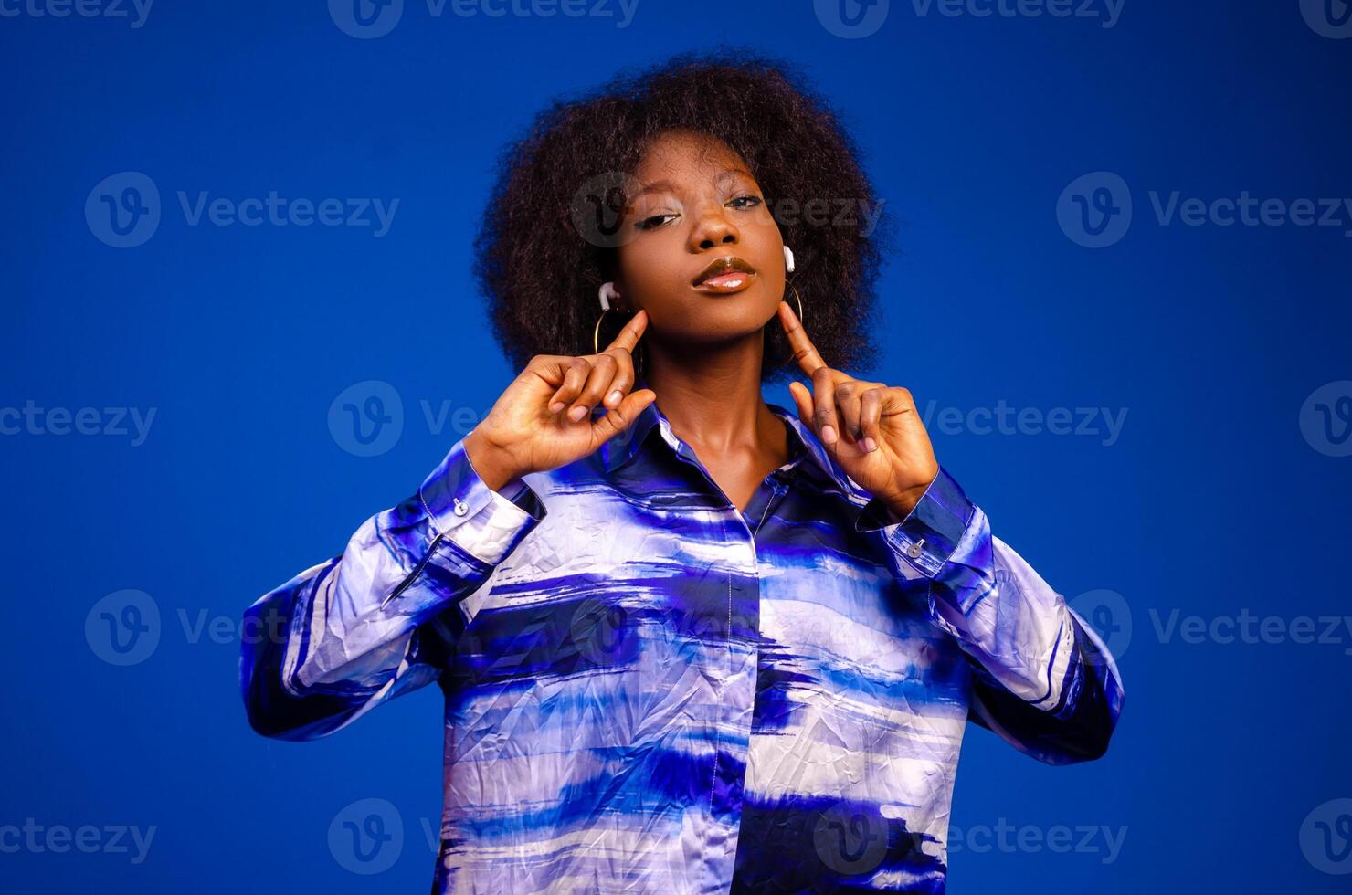 Gorgeous lady listening music in headphones and singing on blue background. photo