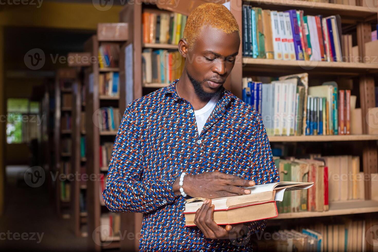 Young man reading book in library photo