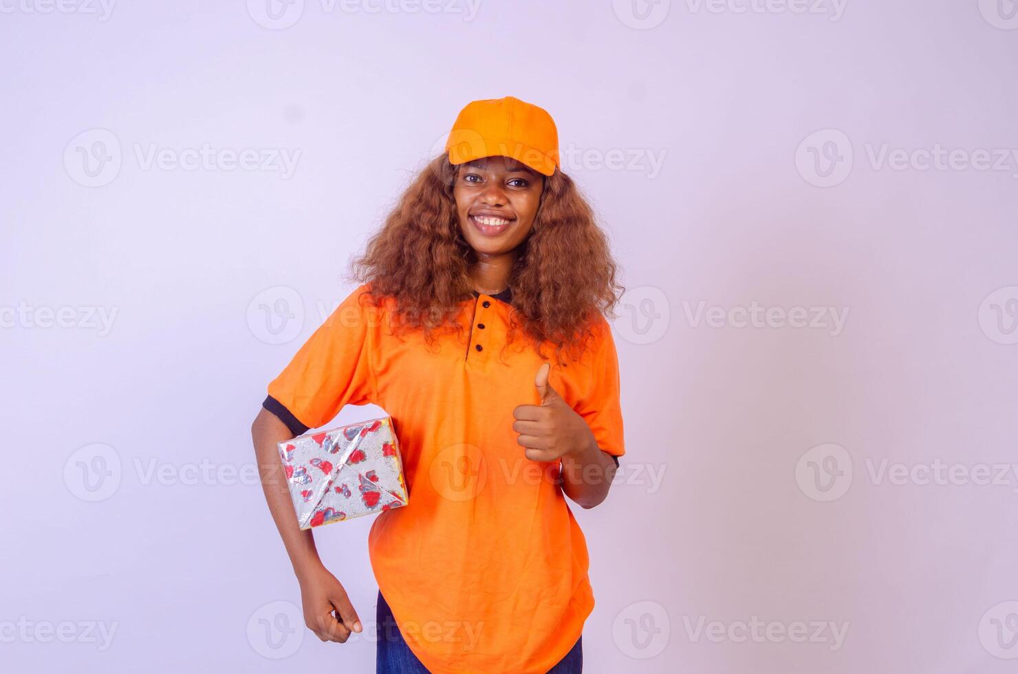 beautiful african female courier worker holding a box, does a thumbs up gesture photo