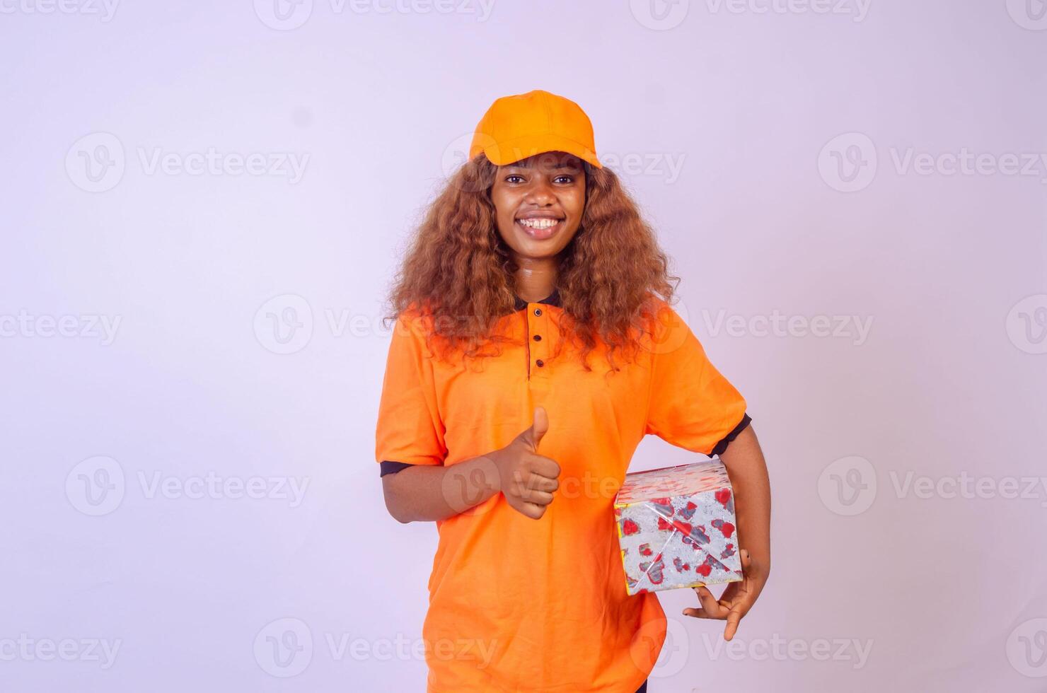 hermosa africano hembra mensajero trabajador participación un caja, lo hace un pulgares arriba gesto foto