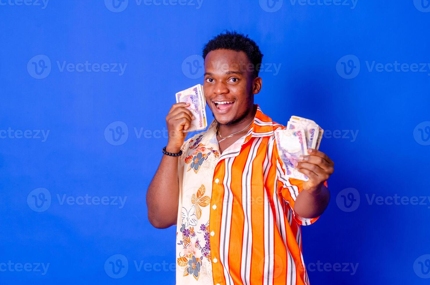 happy and excited young african man holding bundles of cash photo