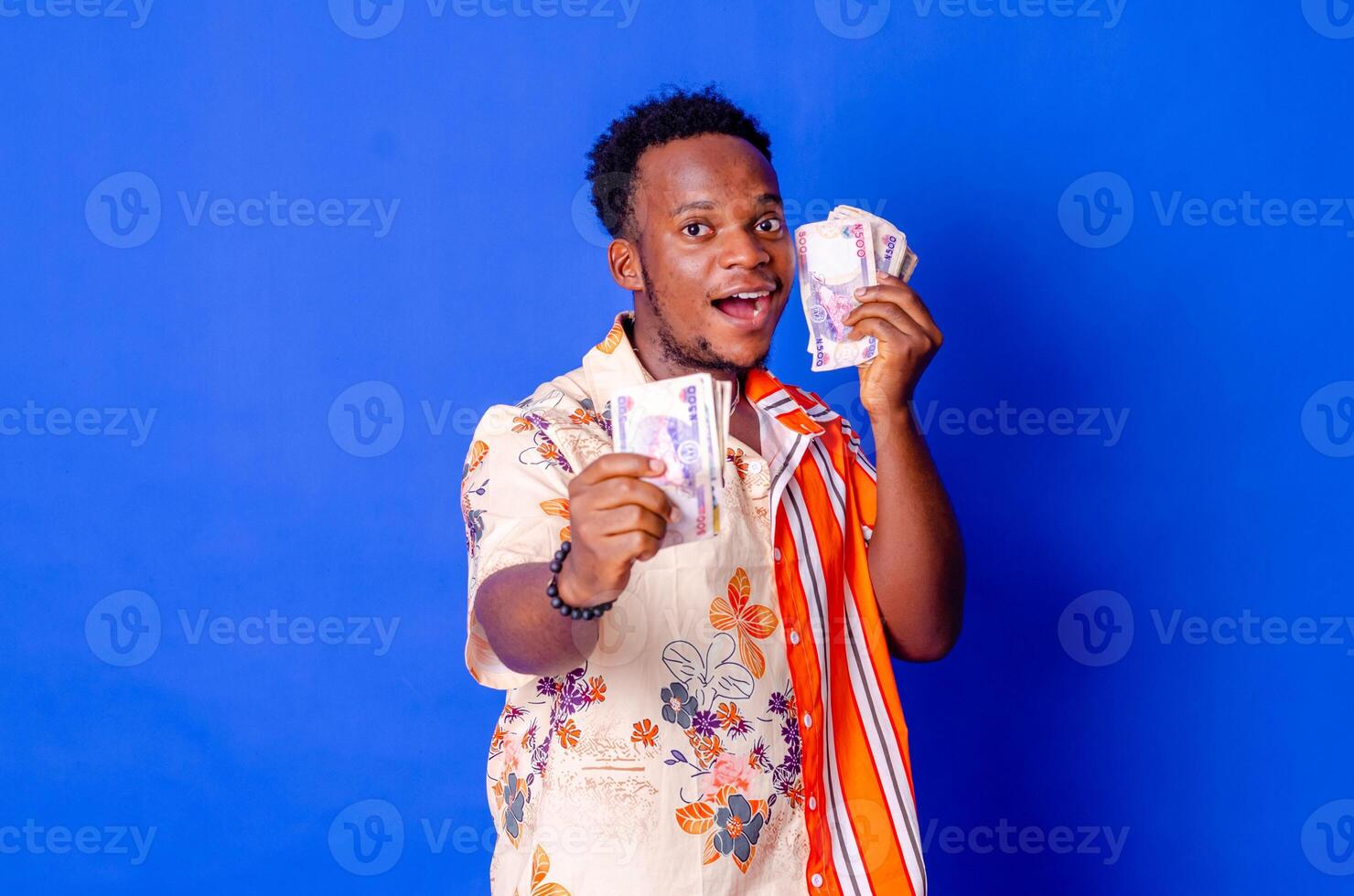 happy and excited young african man holding bundles of cash photo