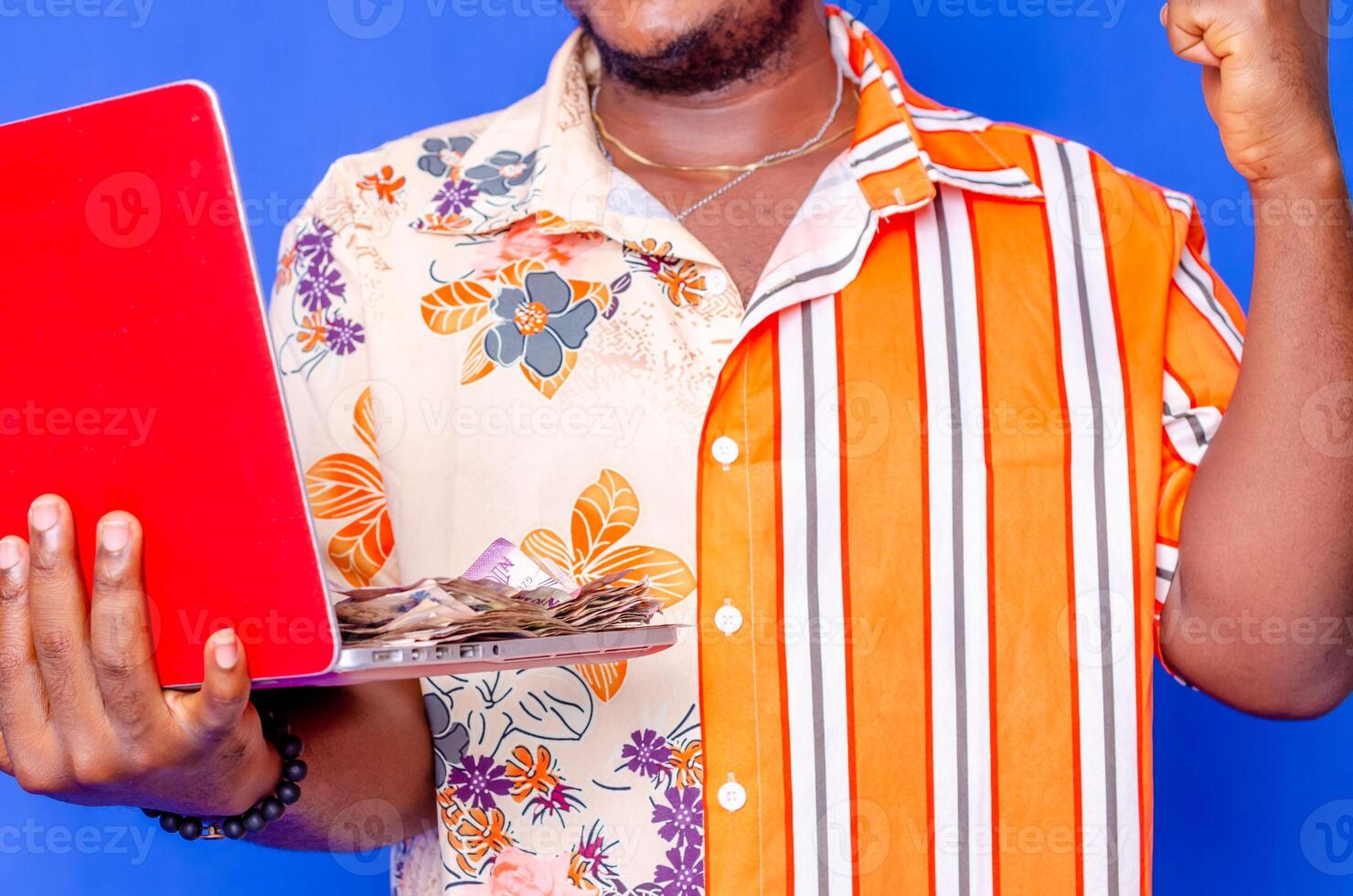 Photo of a happy young afro american handsome man posing isolated over blue wall background using laptop computer holding money.