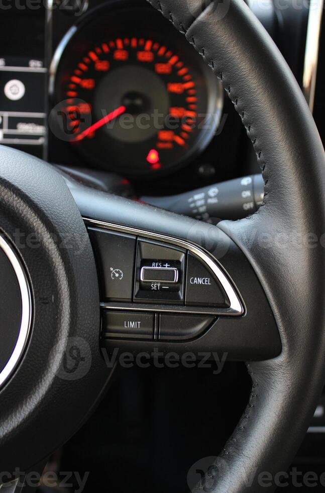View Of Defocused Speedometer With Red Backlight Through Steering Wheel With Speed Control Buttons On It photo