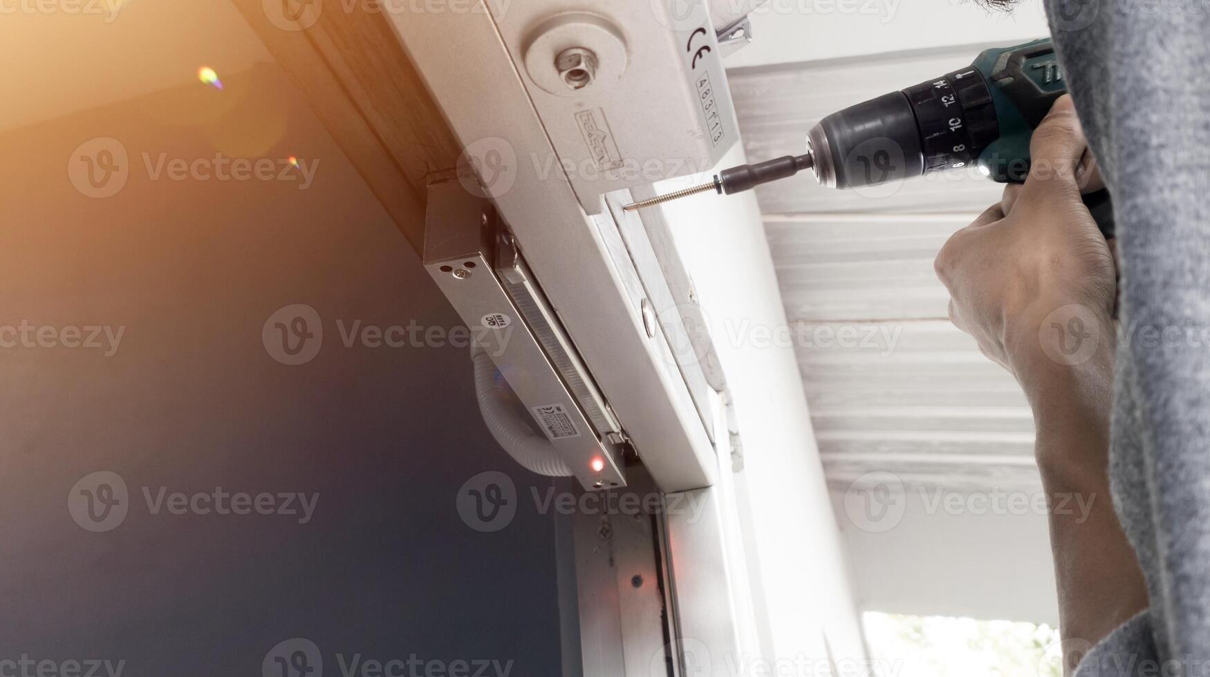 The man installing Magnetic lock system on the door for control of security system.And Installing automatic door closed with shiny light. photo