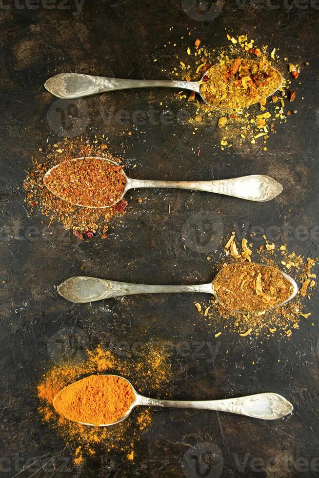 Types of various spices in spoons on a dark table. Cooking food. Flat lay. photo