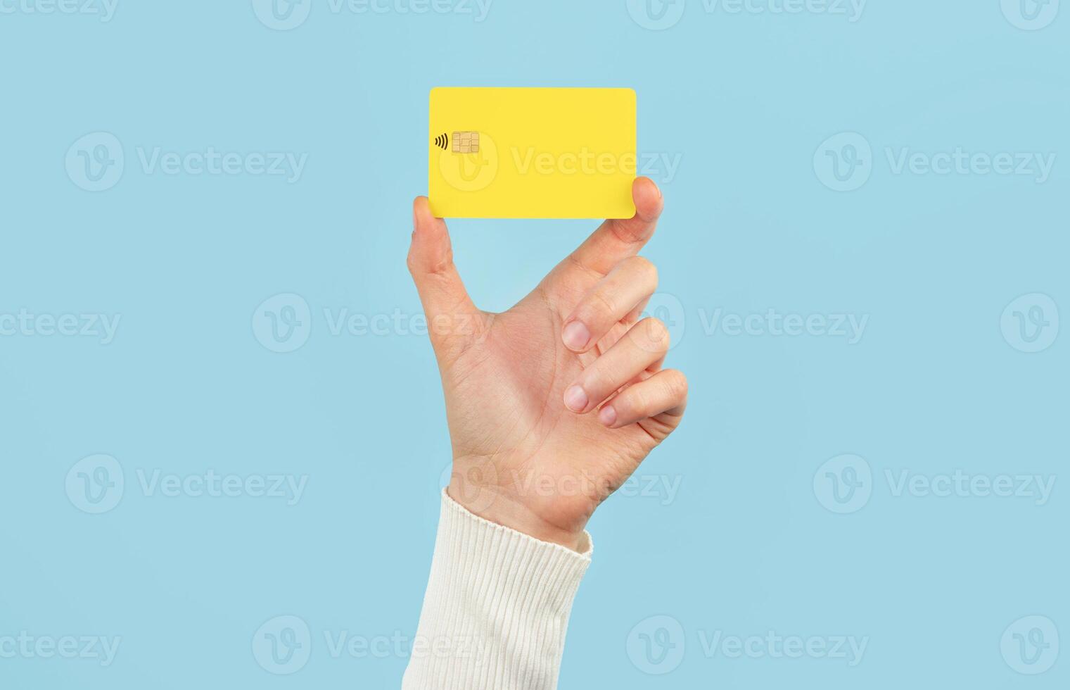 A female hand holds a payment card on a blue background. Bank card layout. photo