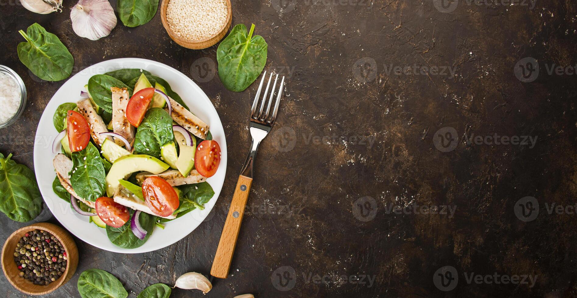 A la parrilla pollo pecho y Fresco vegetal ensalada con Espinacas hojas, aguacate y Tomates en un oscuro antecedentes. ensalada de verduras con carne. cetógeno dieta. dietético nutrición. foto