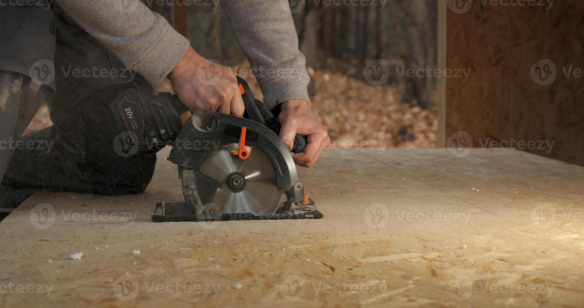 Close-up of a worker's hands using a circular saw to cut plywood. Construction of a new wooden house using frame technology. Carpentry and construction concept. photo