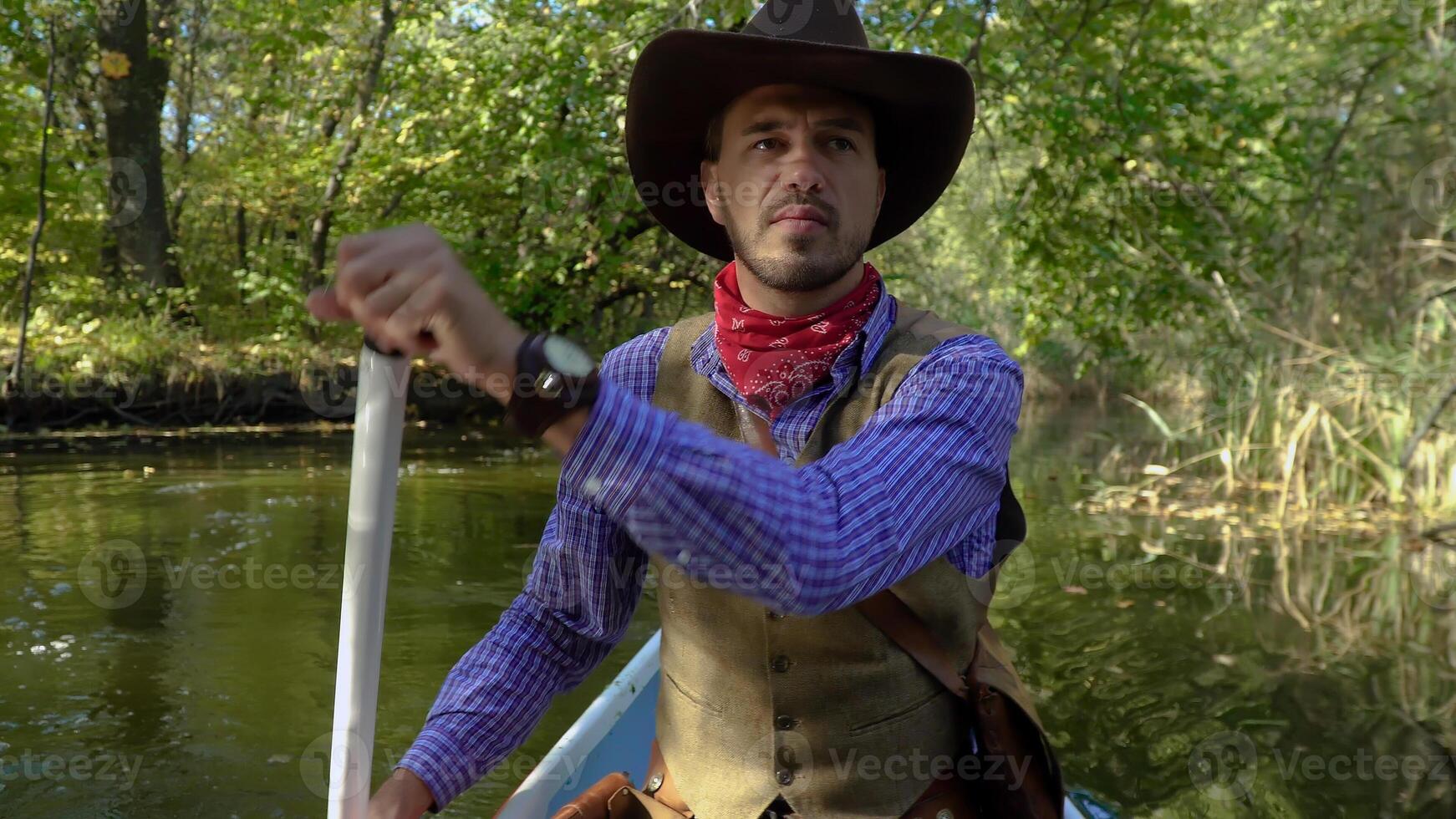 Cowboy in a canoe floats on the river in the forest. Historical reconstruction of life in the wild west of America photo