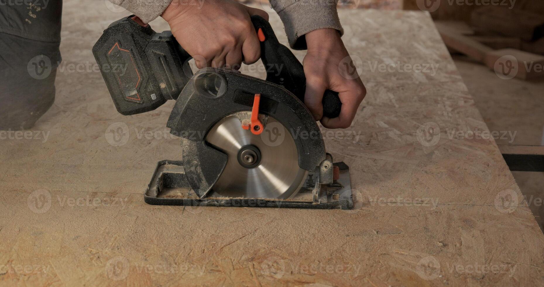 Close-up of a worker's hands using a circular saw to cut plywood. Construction of a new wooden house using frame technology. Carpentry and construction concept. photo