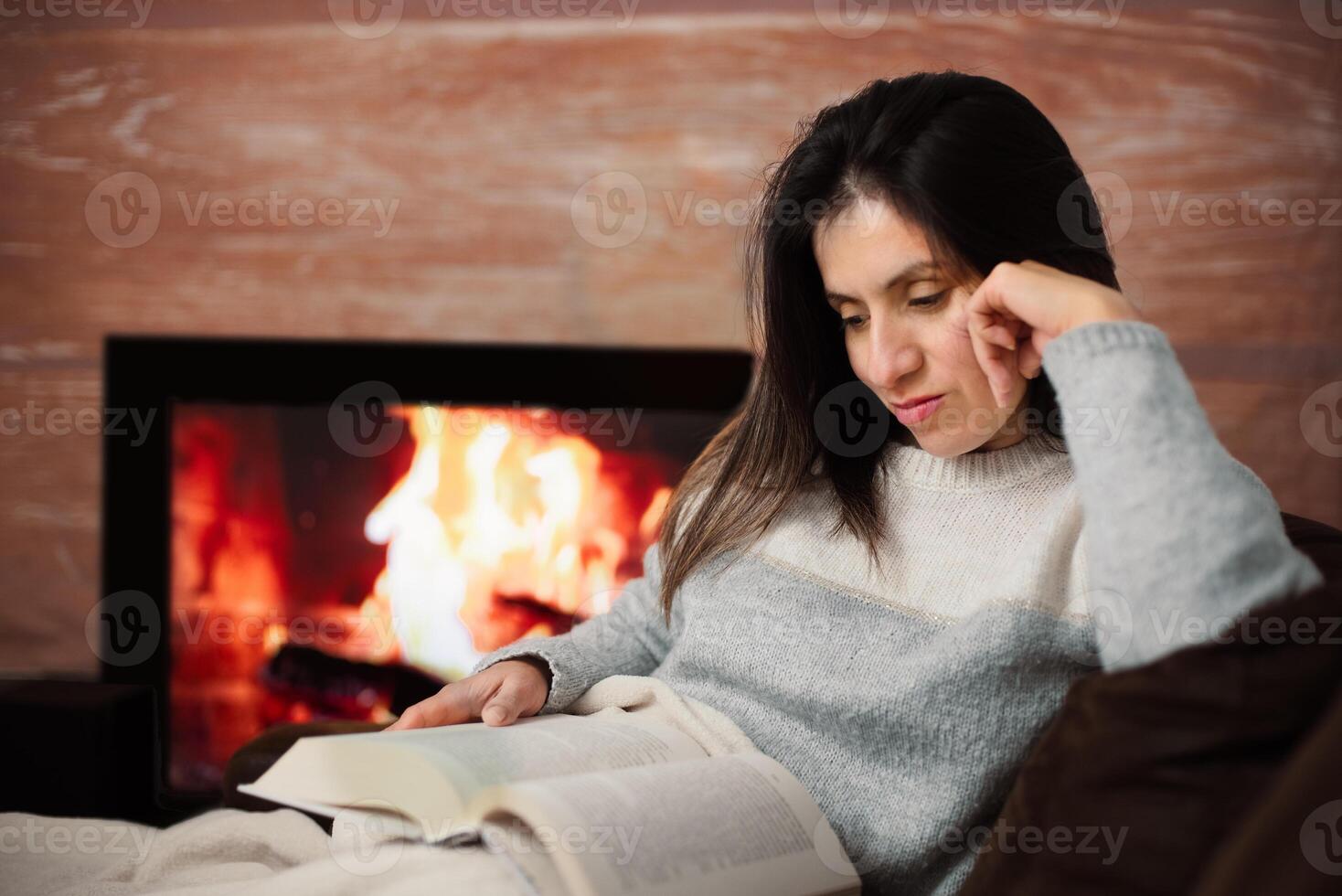 Woman enjoys reading a book from her sofa at home. photo