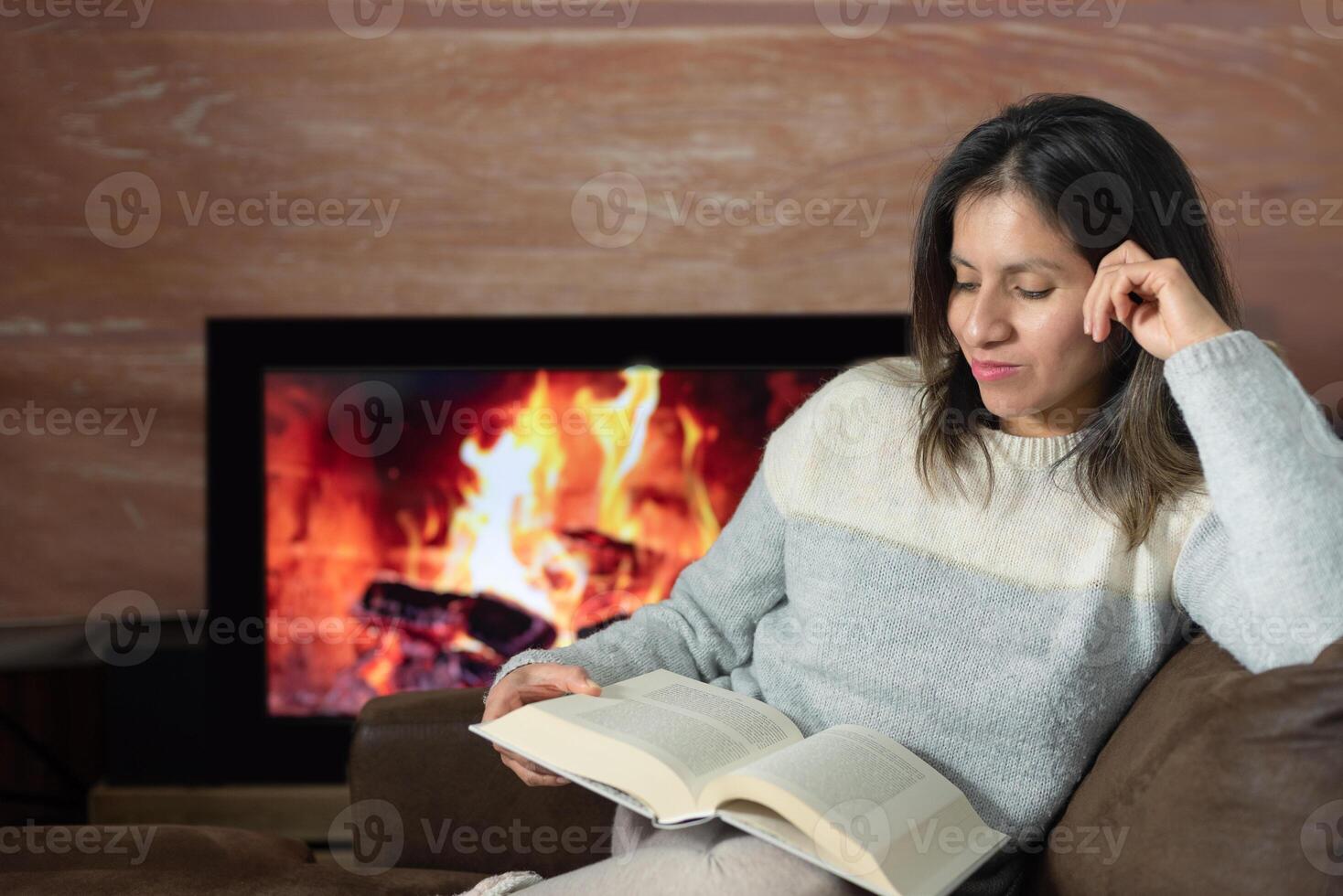 Woman enjoys reading a book from her sofa at home. photo