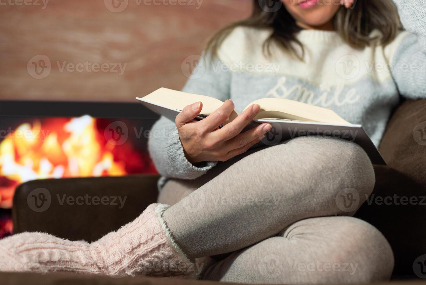 Close-up of woman reading a book in the warmth of her home. photo