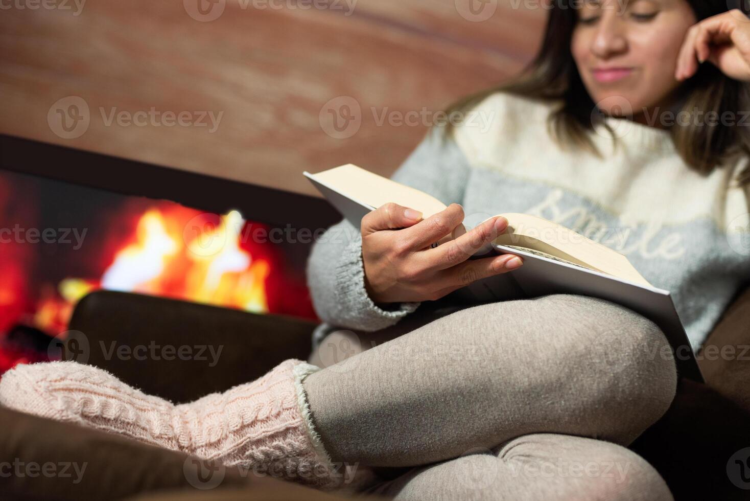 Woman enjoys a rest and relaxes in the warmth of her home by the fireplace. photo