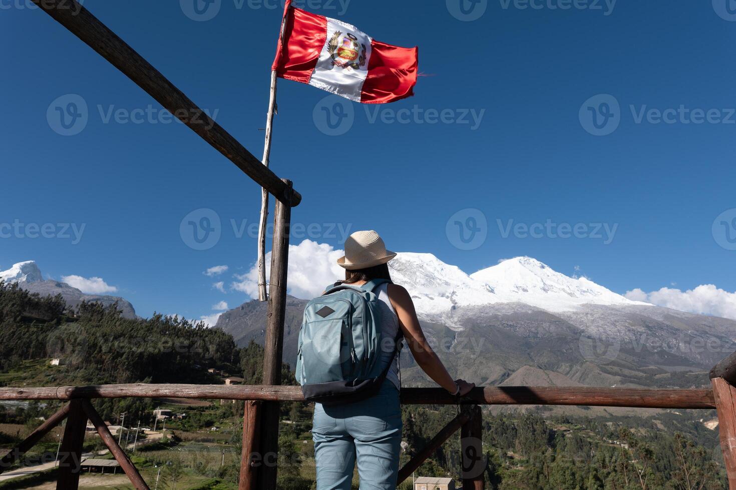 Tourist at a viewpoint with a Peruvian flag observes the mountain named Huascaran. photo