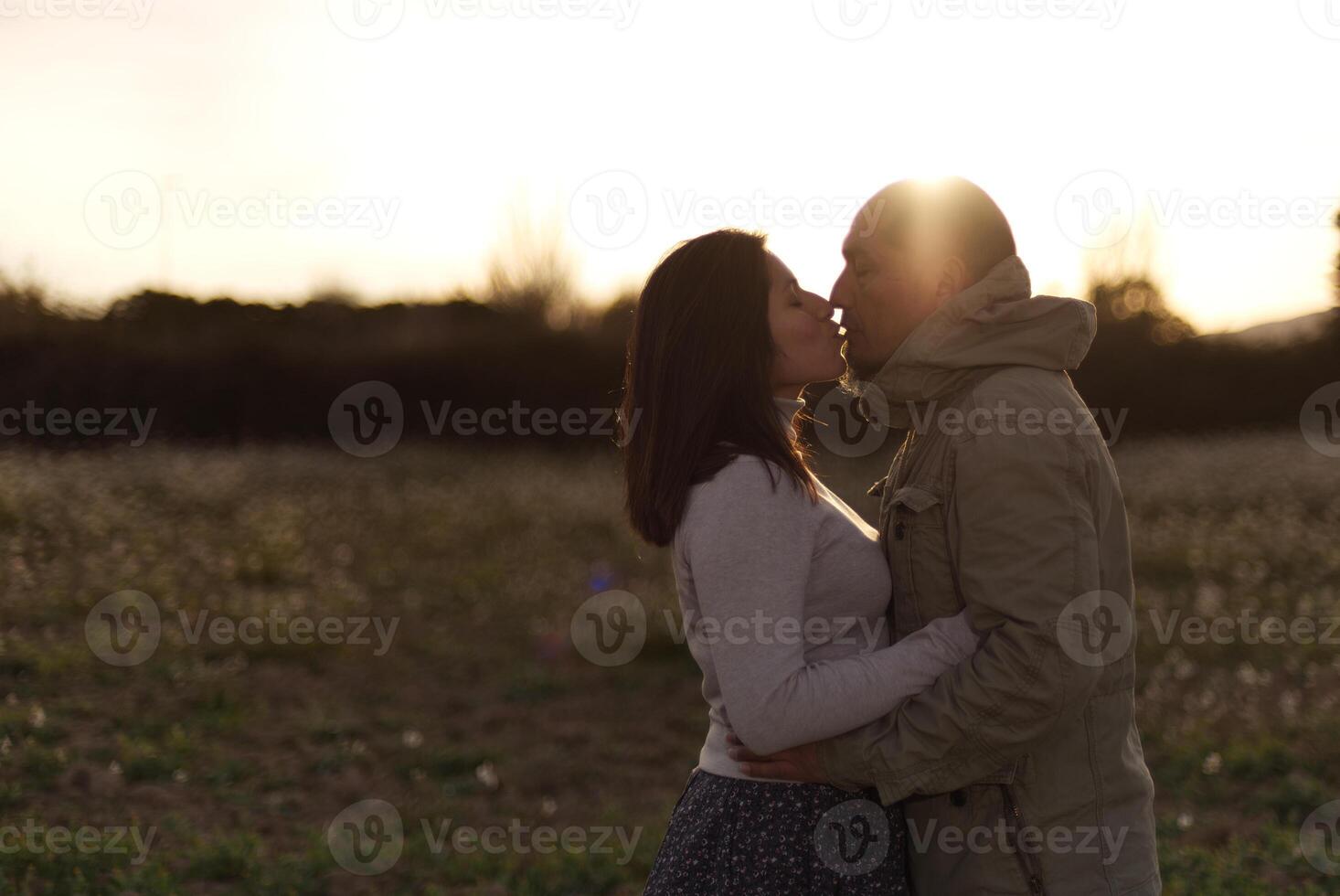 A man hugs and kisses his girlfriend at sunset in a natural environment. photo