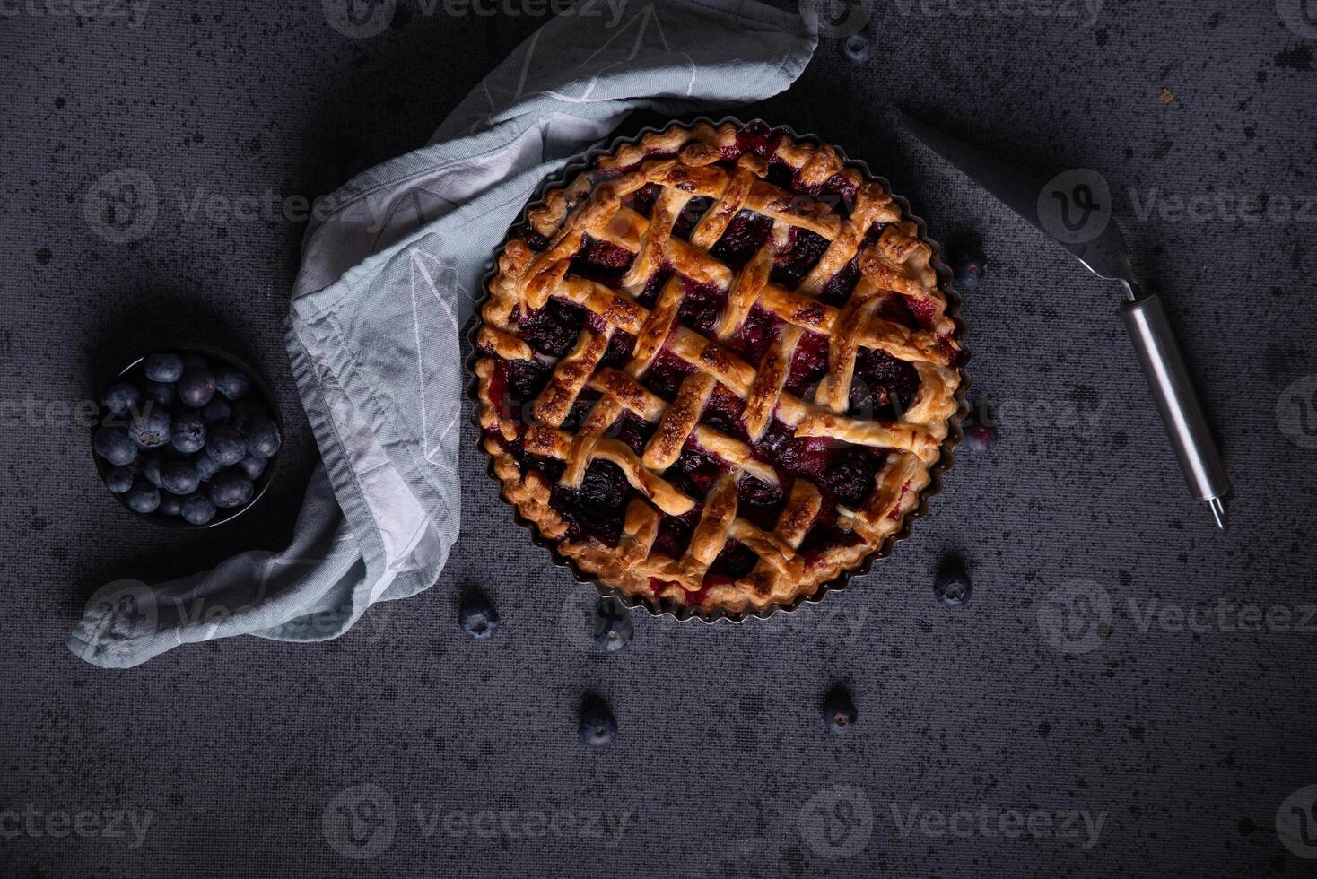 Homemade red fruit and blueberry pie placed on a dark background and viewed from above. photo