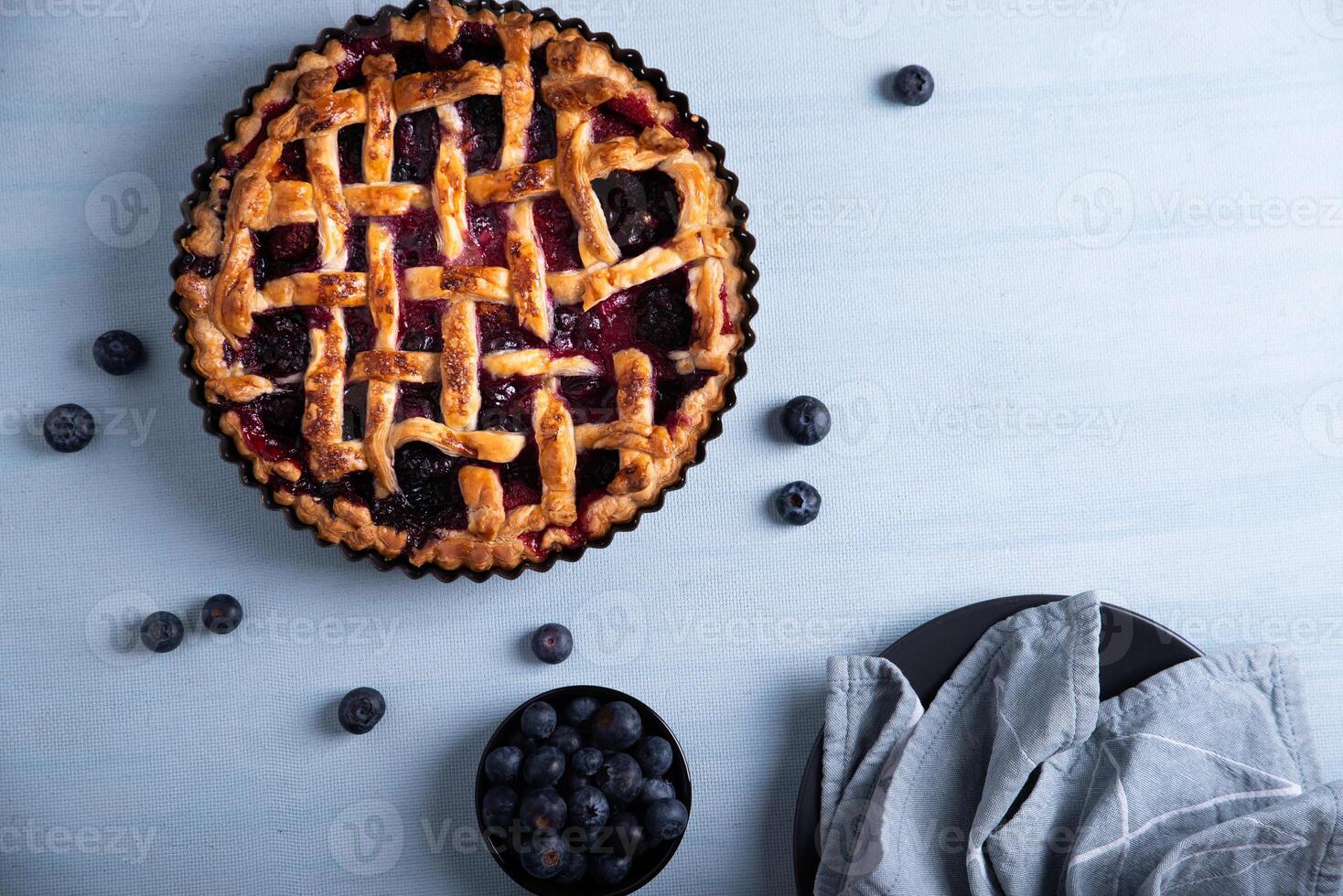 Red fruit and blueberry pie presented on a light blue background, seen from above. photo