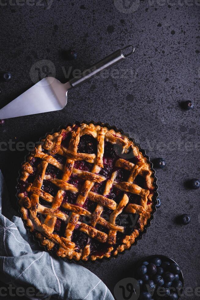 Homemade red fruit and blueberry pie placed on a dark background and viewed from above. photo
