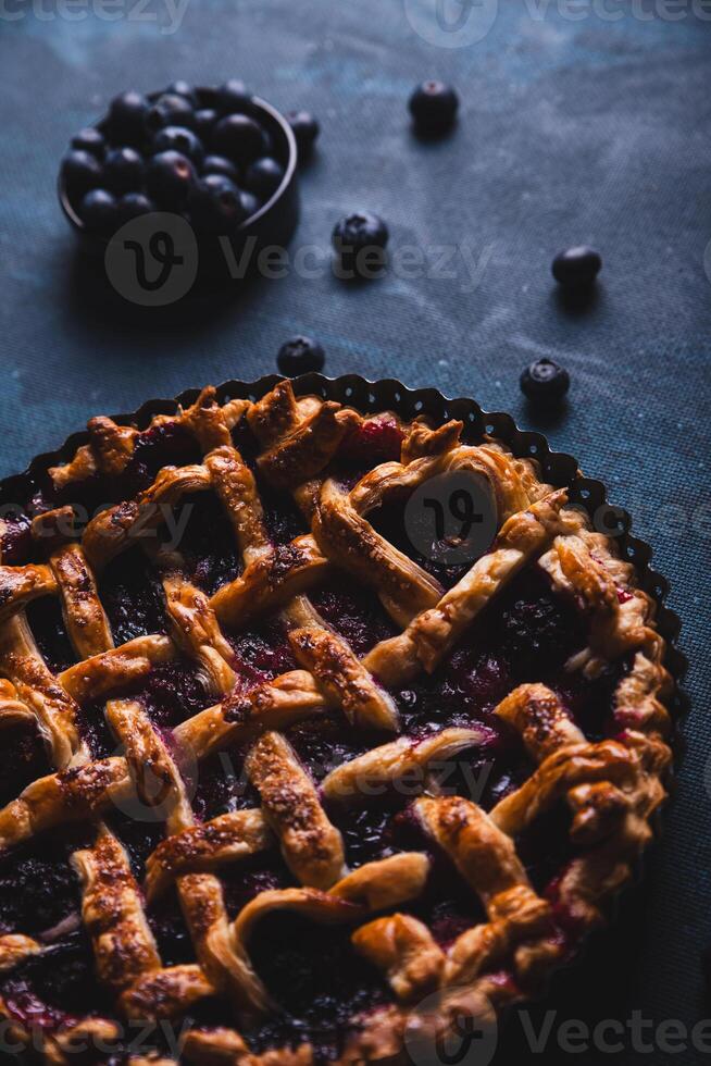 Red fruit and blueberry pie presented on a dark blue background. photo