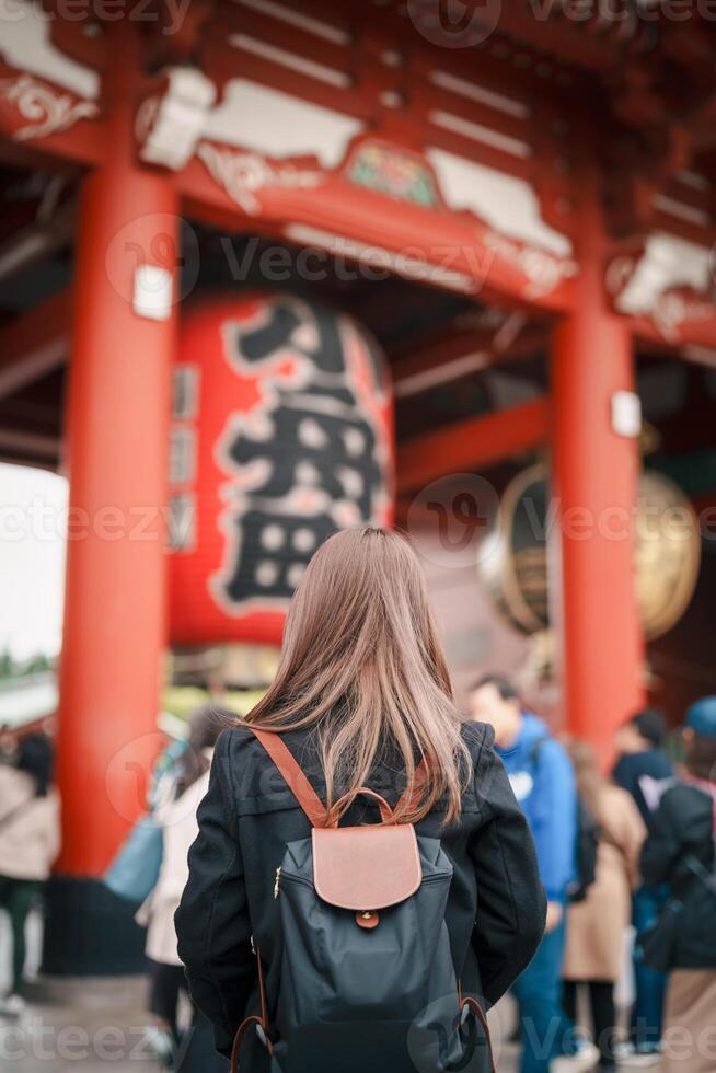 turista mujer visitar sensoji templo o asakusa Kannon templo es un budista templo situado en asakusa, tokio Japón. japonés frase en rojo linterna medio trueno puerta. foto