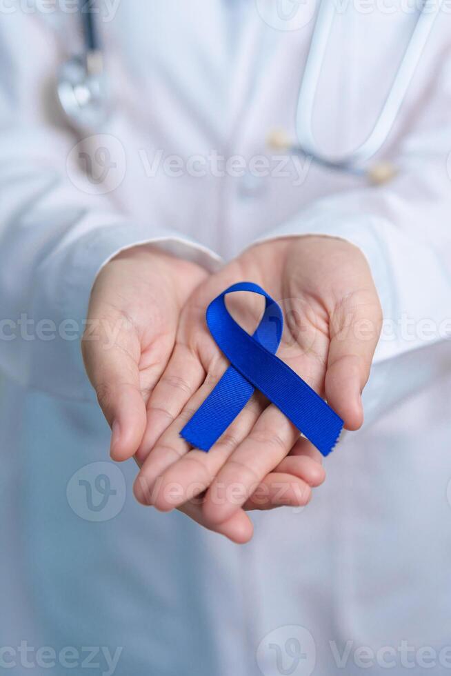 March Colorectal Cancer Awareness month, doctor with dark Blue Ribbon for supporting people living and illness. Healthcare, hope and World cancer day concept photo