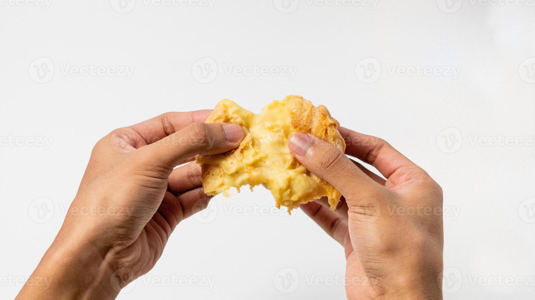 two hands are splitting a Vanilla eclair isolated on a white background photo